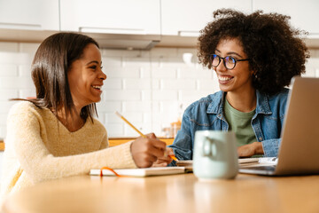 African american woman and daughter doing homework together at home