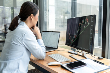 Businesswoman investor having planning a new project and analyzing graph data with display screen the data presented and deal on a stock exchange