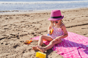a girl applying sunscreen at the beach