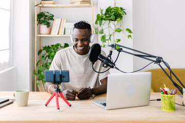 Young adult african man streaming live video at home studio - Millennial content creator male...