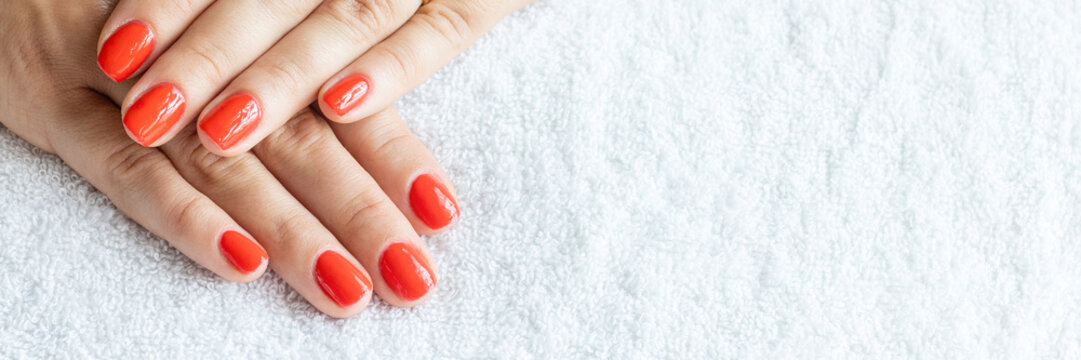Close-up beautiful female hands with red nails on white towel background. Concept hand care, anti-wrinkles, anti-aging cream and spa salon. Soft skin, skincare concept.