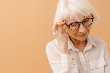 Beautiful senior woman in white shirt adjusting her glasses