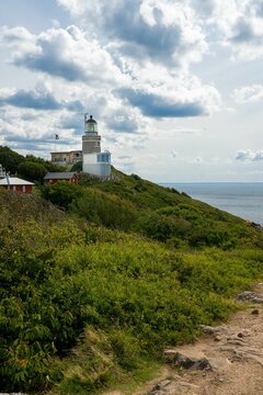Vertical shot of a Kullen Lighthouse under a puffy cloudy sky