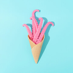 Ice cream cone with pink octopus tentacles with sunny day shadows on bright blue background....