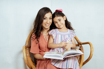 Hispanic mom reading book to her little daughter