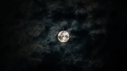 Naklejka na ściany i meble Full moon half hidden by clouds. Night photography