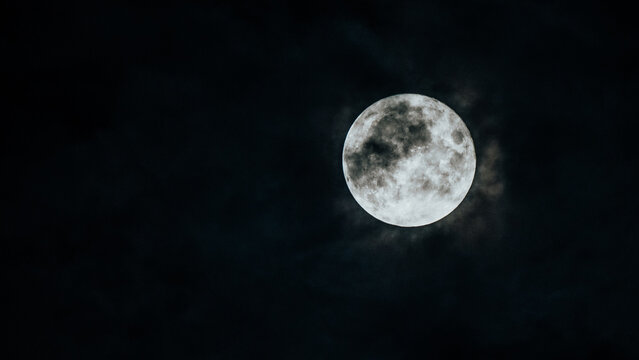 Full moon half hidden by clouds. Night photography