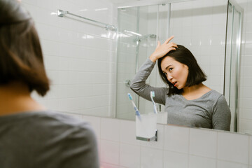 Young asian girl adjusting hair in front of a mirror