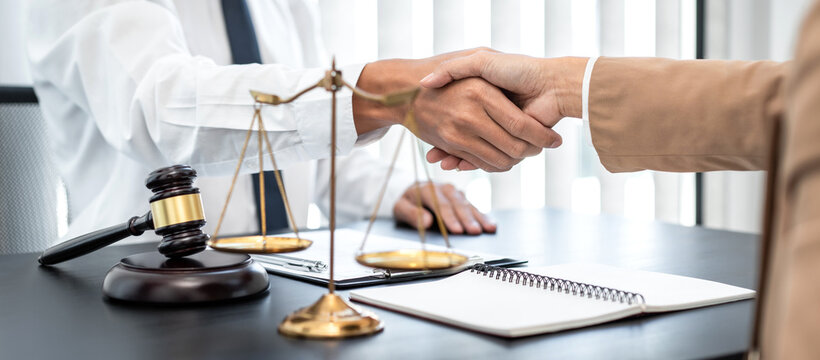 Businesswoman shaking hands with Professional male lawyer after discussing a good deal of contract in the courtroom, Concepts of law, Judge gavel with scales of justice