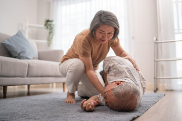 Asian senior wife helping husband fainting and falling on the ground in the living room. Elderly...
