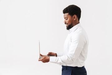 Black bearded man wearing shirt smiling and working with laptop