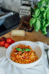 Served plate of just cooked homemade fettuccine pasta with creamy tomato sauce, seafood and parmesan cheese, decorated with basil leaves on the kitchen table. Selective focus