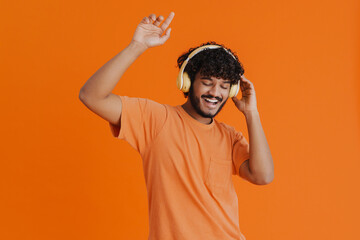 Young handsome indian smiling man in headphones enjoying music