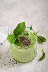 Spinach smoothie healthy green. Vegan smoothie or milkshake from spinach, banana and chia seeds on gray concrete table background. Clean eating, alkaline diet. Top view. Mock up.