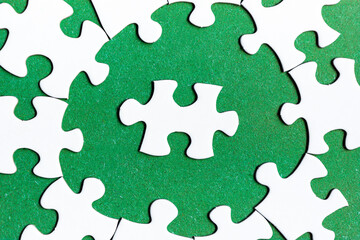 White jigsaw puzzle with some missing pieces on green background. Flat lay.