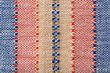 Plain weave fabric background macro. Cloth with vertical stripes of yellow, red and blue colors. Textile texture surface detail. Design element of colorful woven fabric. Weft and warp.