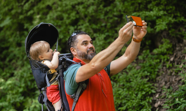 Young man and his baby girl in a backpack carrier on a hike