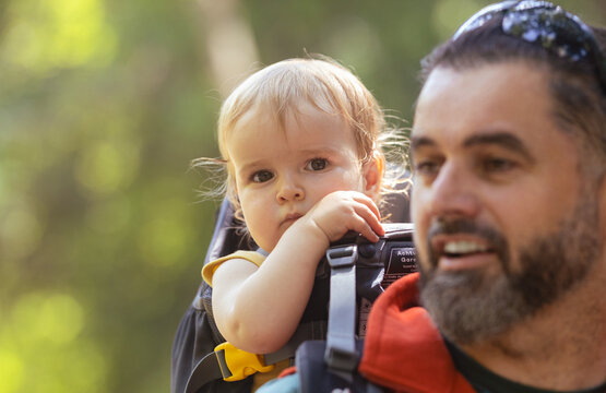 Young man and his baby girl in a backpack carrier on a hike