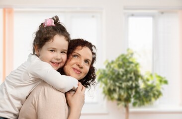 Mother and her little child happily smile and hug in apartment. Happy family.