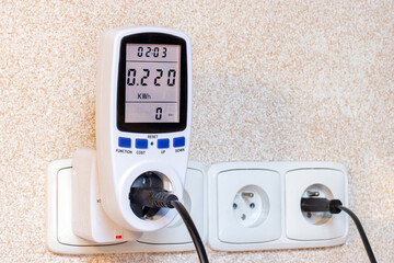 Wattmeter for measuring electricity costs connected to the outlet, close-up