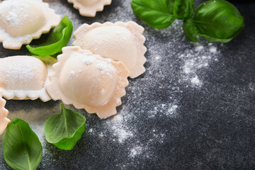 Ravioli Italian food. Tasty homemade with flour, tomatoes, eggs and greens basil on dark background. Food cooking ingredients background. Top view.