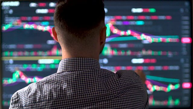 Male trader working with set for analyzing financial statistics and market data.