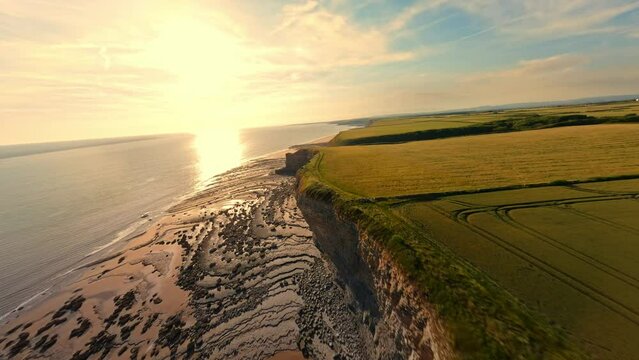 4K FPV Aerial view of monk nash beach known as the jurassic coast, stunning fast flying low across golden sandy beach with cliff side on the right.