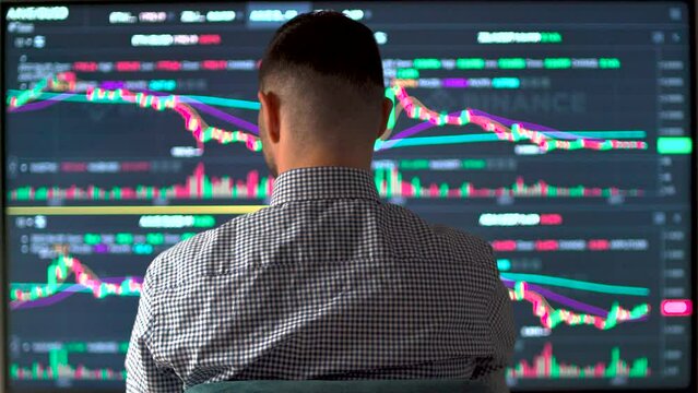 Stock market broker analyzing data and graphs on multiple computer monitors