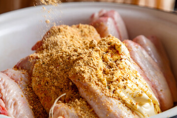 Dish with fresh raw wings sprinkled with spices on a wooden table.
