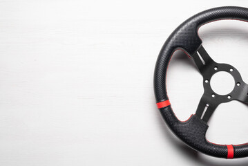 A sport car steering wheel on the white flat lay background with copy space.