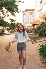 Cute little girl with a straw hat in her hands enjoys summer and life
