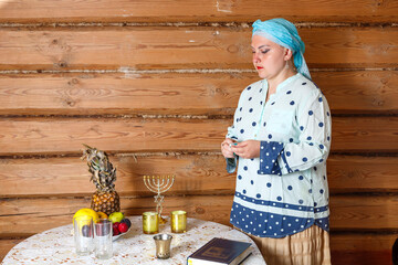 A Jewish woman in a traditional headdress prepares for Shabbat.