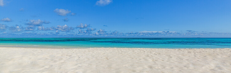 Fototapeta premium Closeup sand beach sea waves and blue summer sky. Panoramic beach landscape. Empty tropical beach and seascape, horizon. Bright exotic coast calmness, tranquil seaside nature view relaxing sunlight