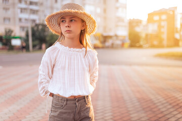 beautiful little girl with freckles on her face. Girl in a white blouse and with a straw hat on his...