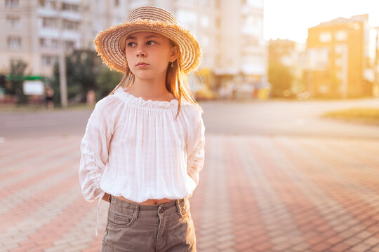 beautiful little girl with freckles on her face. Girl in a white blouse and with a straw hat on his head