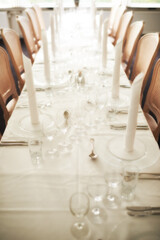Empty fine dining room table arranged for dinner in fancy restaurant. Above view of glass dishes, cups, wineglasses, silverware and cutlery neatly organized for lunch. Seating in hospitality industry
