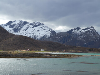 Landscape view of mountain snow and a lake fjord in polar and arctic circle of Norway. Snowcapped terrain and hills in remote area with clouds in cold winter. Traveling overseas for holiday, vacation