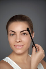 Beauty model. Correcting and contouring eyebrows. Beautiful woman shaping brows with comb.