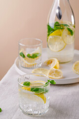 Refreshing summer drink with lemon and mint on the table. Lemonade in glasses and bottle