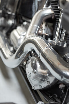 Chrome plated bend exhaust outlet pipe of a modern motorbike. An engine block with the exhaust pipe of the latest motorcycle. Motorcycle engine clutch casing with shiny chrome parts closeup detail