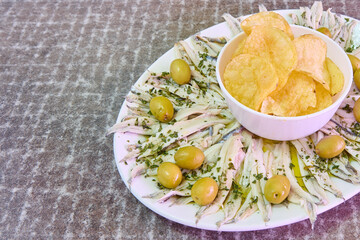 plate with anchovies in vinegar, chips and olives