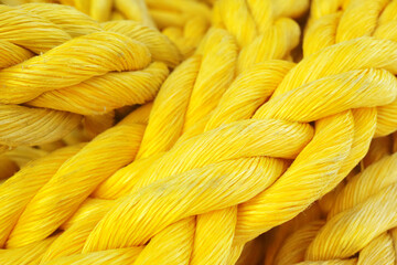 Closeup of a strong and colorful yellow rope. New heavy duty marine ropes on a sailing vessel. Macro of bright yellow color synthetic rope. Texture of twisted or braided polypropylene rope, copyspace