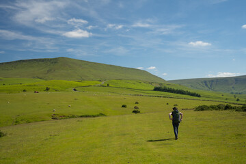 Hiker with backpack and hat walks on Offa's Dyke Path in Wales close to the Black Mountains