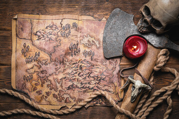 Map of ancient lands. Ancient journey concept. Old map and battle axe on the wooden flat lay table background.