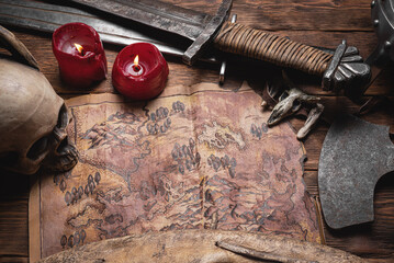 Map of ancient lands. Ancient journey concept. Old map and battle axe on the wooden flat lay table...