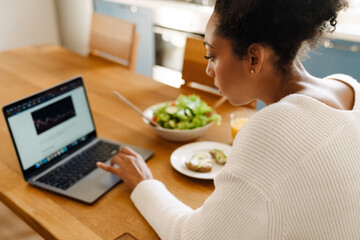 Back view of african woman looking on laptop during lunch