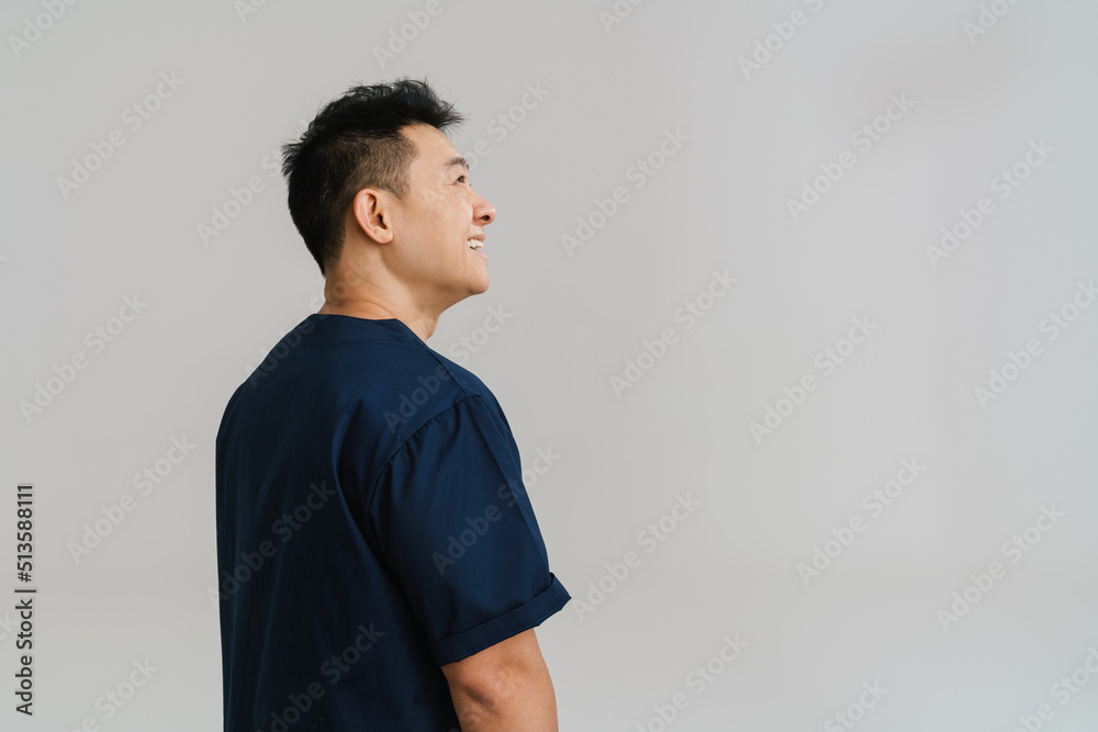 Wall mural Adult asian man wearing medical uniform posing at camera