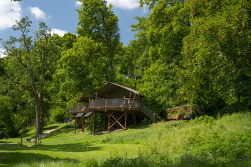 Fototapeta na wymiar Wooden glamping tree top house with balcony on a grass field on Hay-on-Wye in Wales