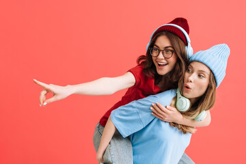 Two young happy girls with headphones doing piggyback ride