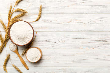 Flat lay of Wheat flour in wooden bowl with wheat spikelets on colored background. world wheat crisis